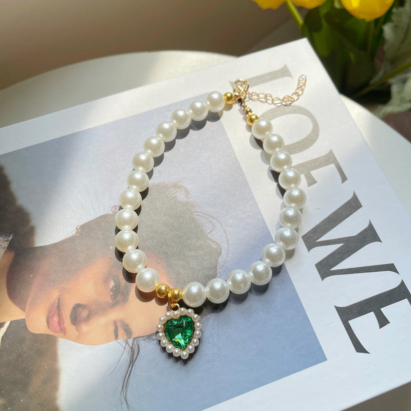 Pearl necklace with a green heart pendant on a magazine