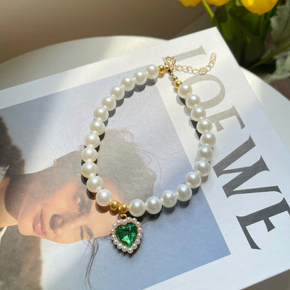 Pearl necklace with a green heart pendant on a magazine