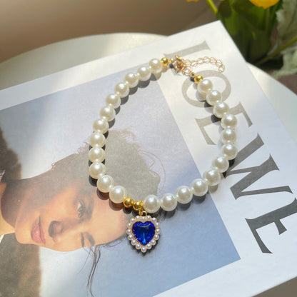 Pearl bracelet with a blue heart charm on a magazine